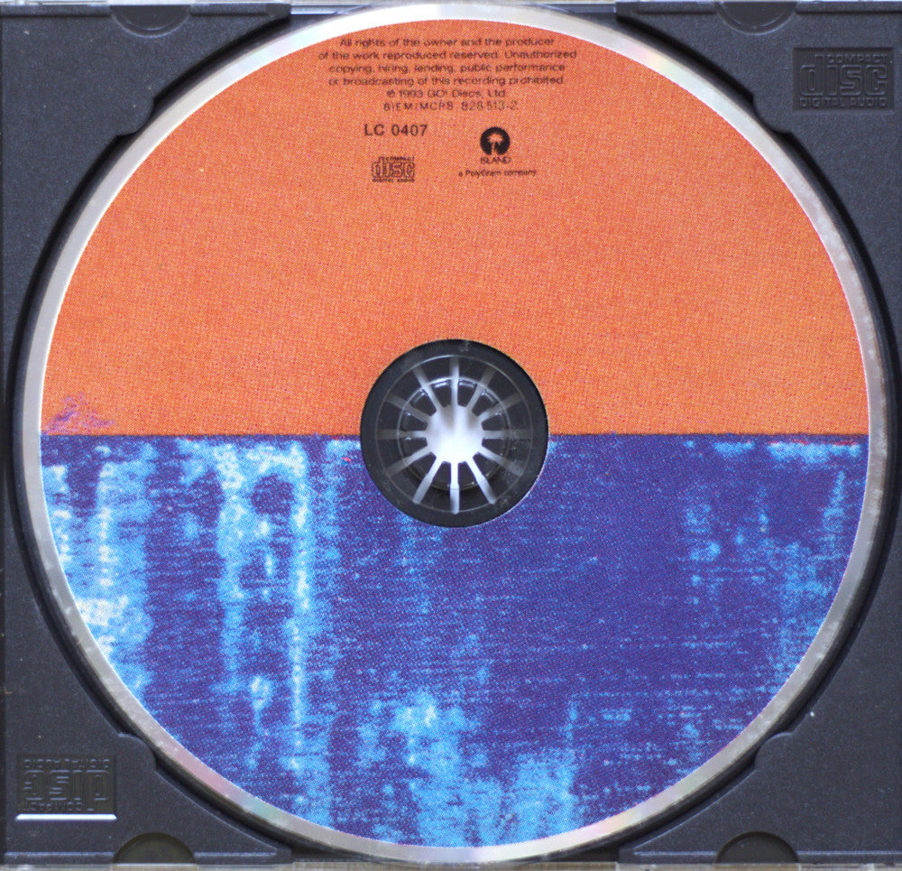 A close-up of a CD disc inside a black jewel case, showing the back side of the disc with an orange upper half and a blue lower half with a white starburst center.