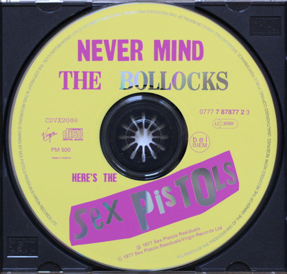 A CD single cover for Sex Pistols' 'Never Mind The Bollocks', featuring a bright yellow disc with bold pink and blue text and the band's name in large pink lettering.