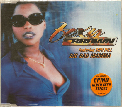 CD cover for Foxy Brown 'Big Bad Mama' featuring Dru Hill, with a portrait of a woman in sunglasses and a blue top against a blue gradient background. The title 'Big Bad Mama' is printed in large gold and black text, with an orange circular sticker reading 'EPMD Never Seen Before'.