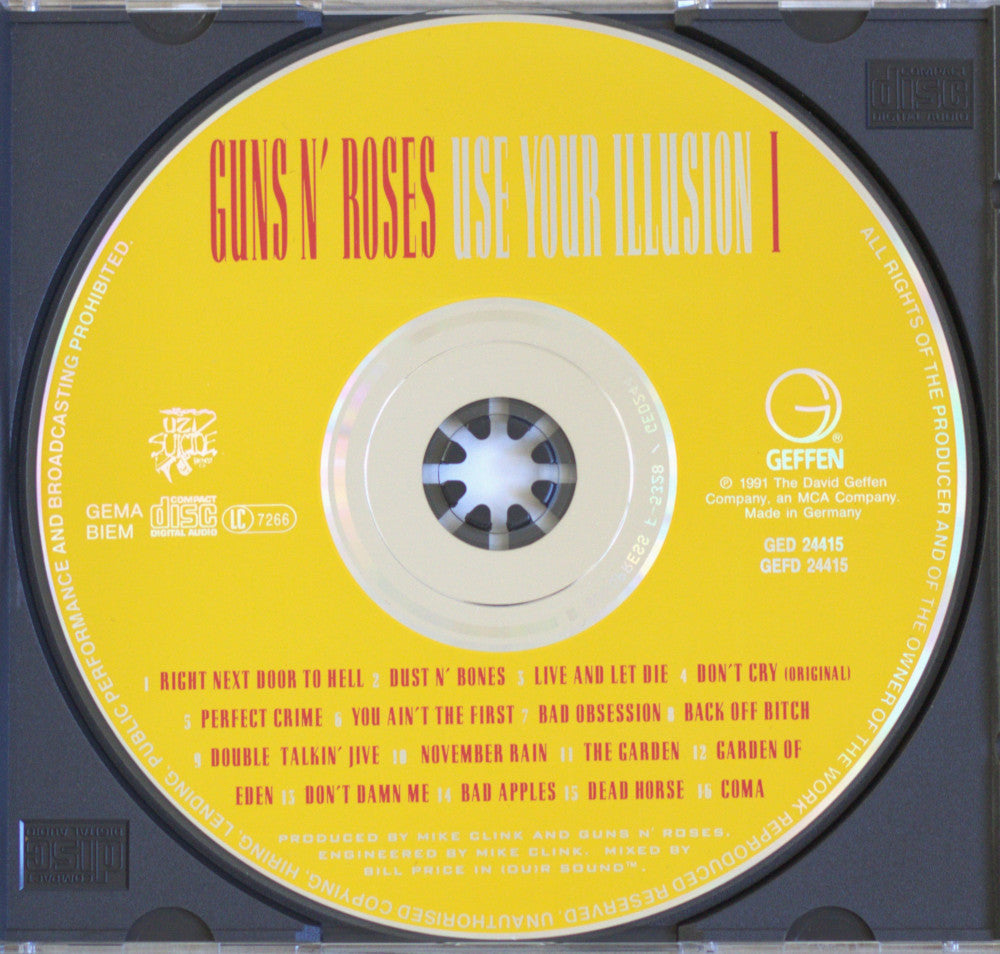 A compact disc for Guns N' Roses's 'Use Your Illusion I' with a bright yellow label and black outer ring, photographed inside a clear jewel case.