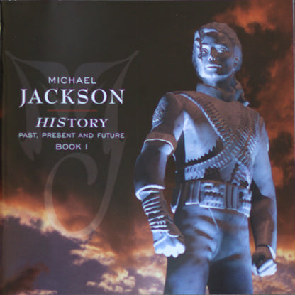 Book cover for 'Michael Jackson: History - Past, Present and Future Book 1' featuring a stylized blue-toned statue of Michael Jackson against a dramatic fiery sky background.