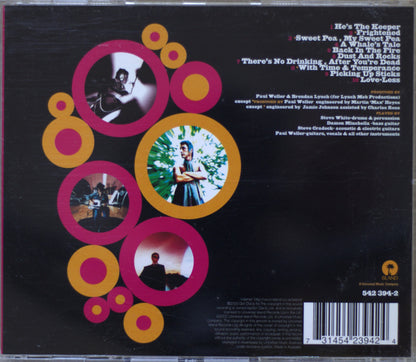 The back cover of a Paul Weller album on CD, featuring a black background with retro pink, orange, and yellow circular graphics, tracklist text, and a barcode.
