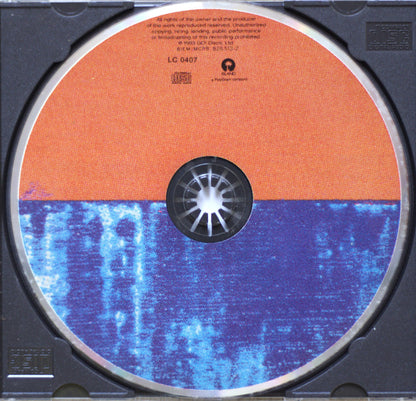 A close-up of a CD disc inside a black jewel case, showing the back side of the disc with an orange upper half and a blue lower half with a white starburst center.