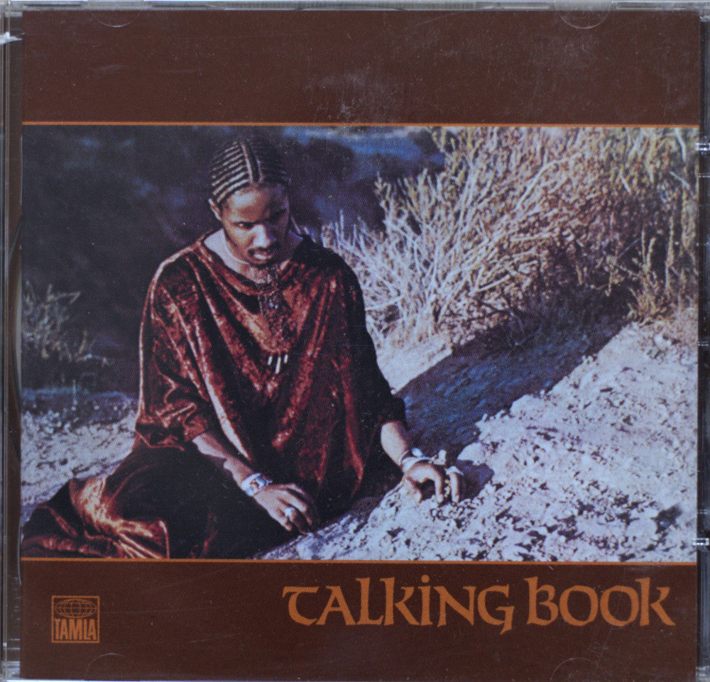 Stevie Wonder - Talking Book CD cover featuring a seated woman in a rust-red robe against a desert-like background, with the title 'TALKING BOOK' in large brown text at the bottom.