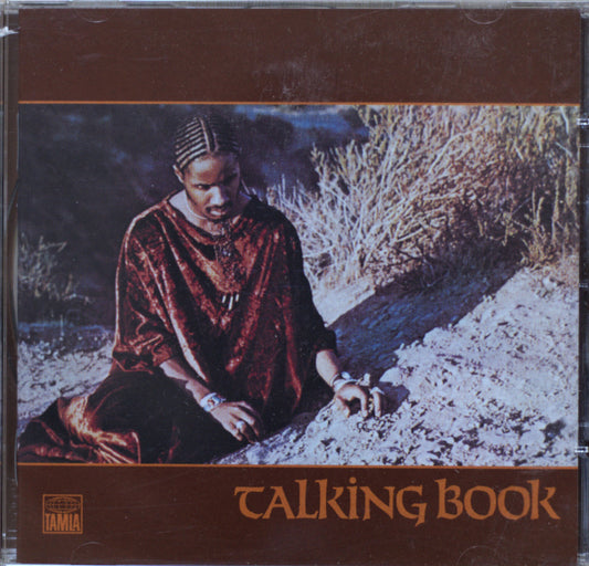 Stevie Wonder - Talking Book CD cover featuring a seated woman in a rust-red robe against a desert-like background, with the title 'TALKING BOOK' in large brown text at the bottom.