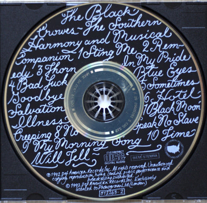 A close-up of a CD disc with handwritten-style blue text listing song titles around the outer ring, and the center label reading 'The Black Crowes' and 'BiM Stemma'.