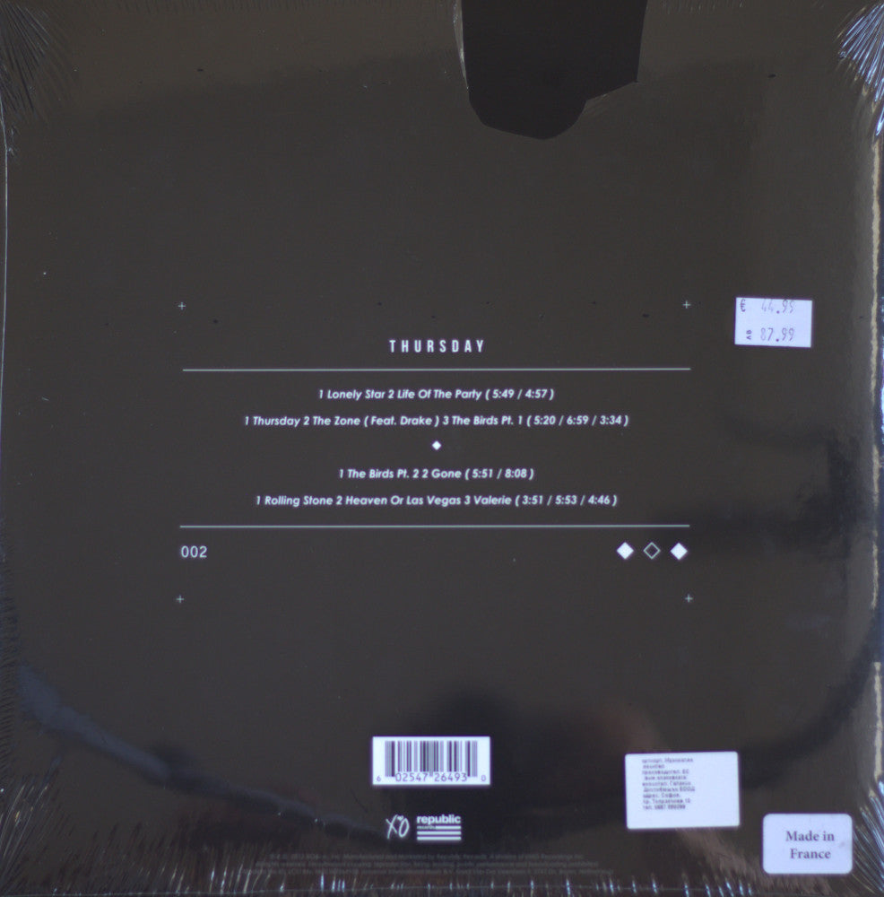 The back of a Thursday album cover by the The Weeknd, wrapped in clear plastic, showing track listings, barcode, and a small 'Made in France' label on a dark background.