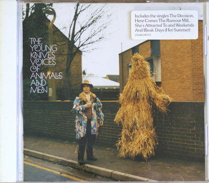 CD cover for The Young Knives' 'Voices of Animals and Men', featuring a person standing on a street next to a tall figure made of straw, with a white text box listing included singles.