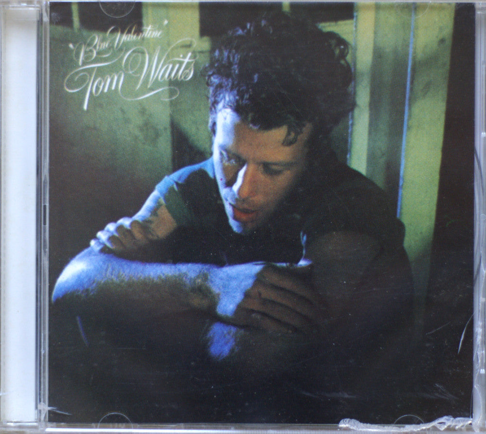 Tom Waits 'Blue Valentine' CD album cover in its clear plastic jewel case, showing the artist seated in a dim interior with greenish light and white script title text.